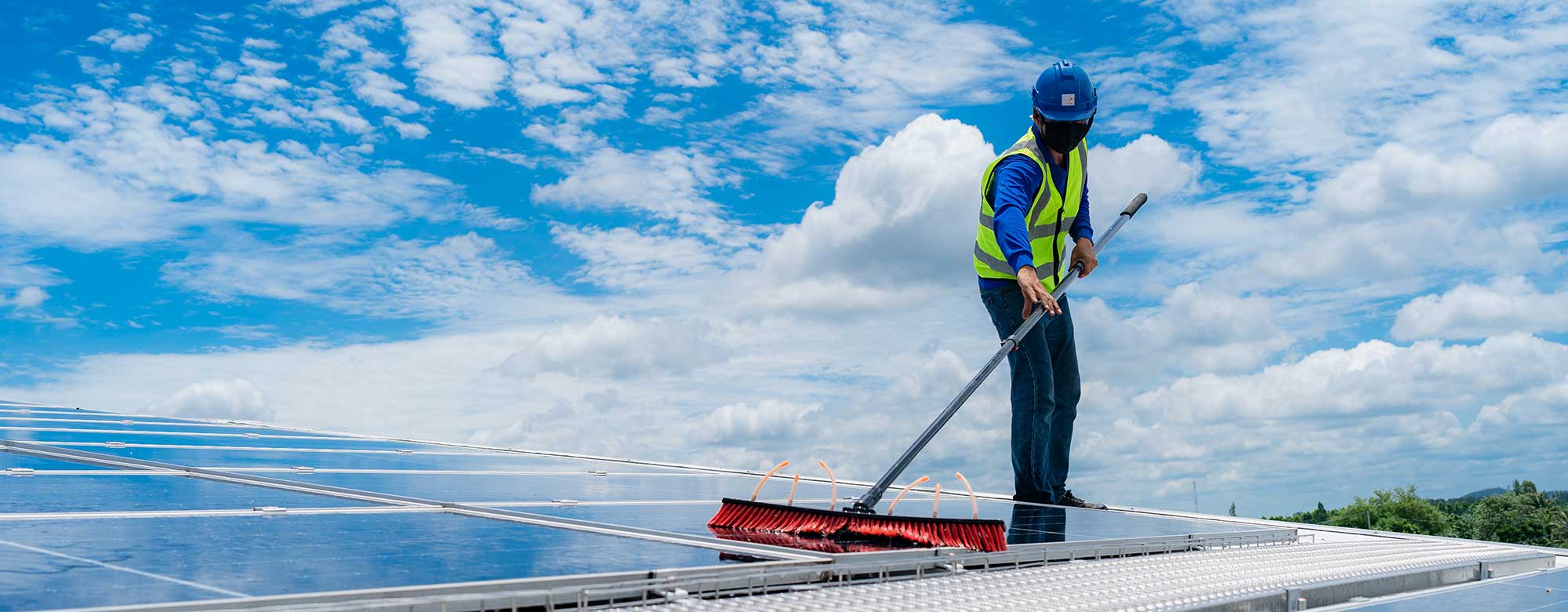 Technician cleaning solar panels on roof